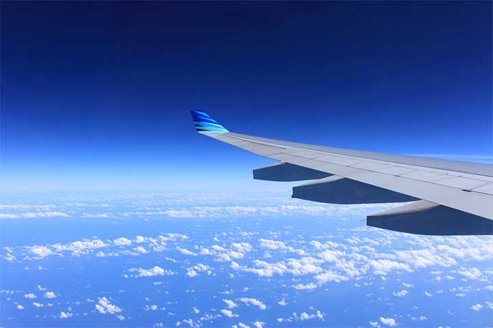 Plane wing in sky above clouds