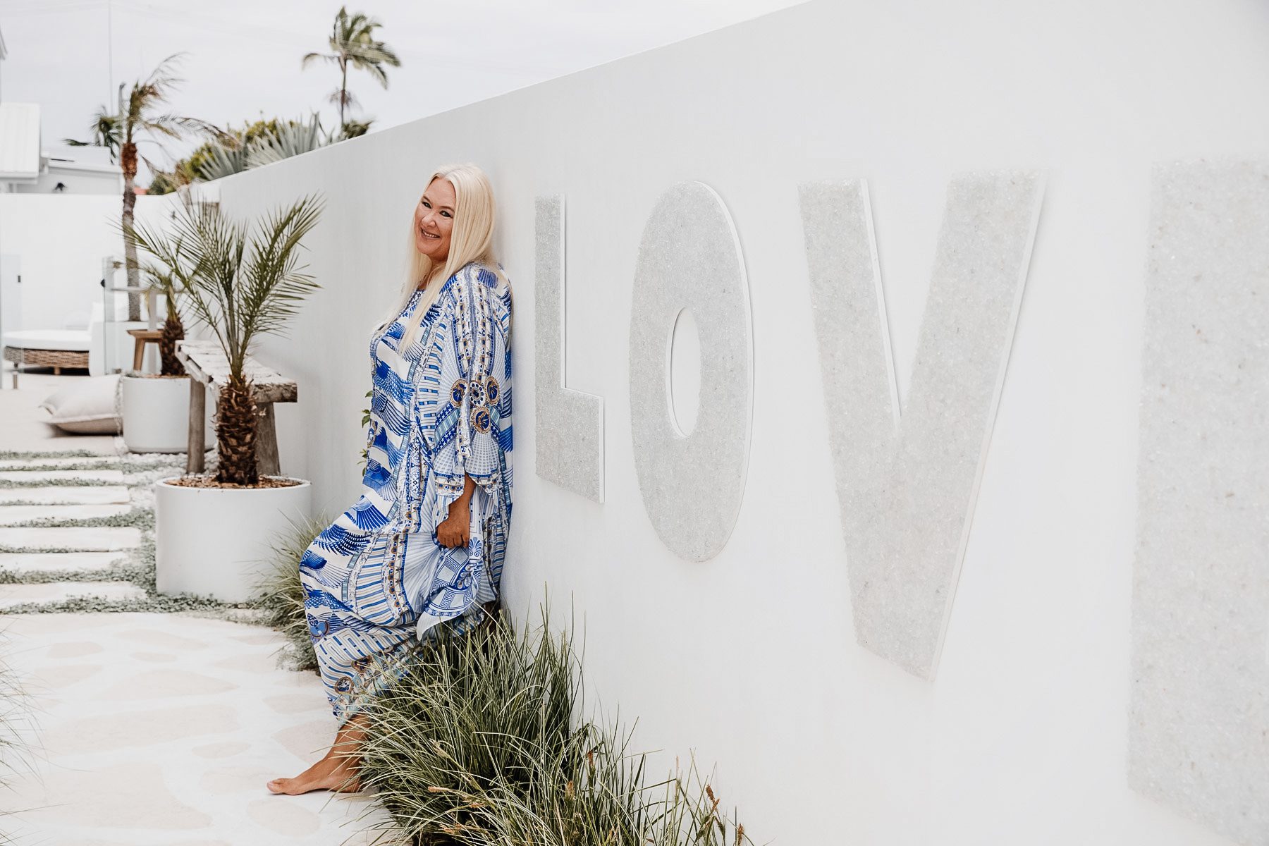 Zoe Watson standing against wall in blue kaftan